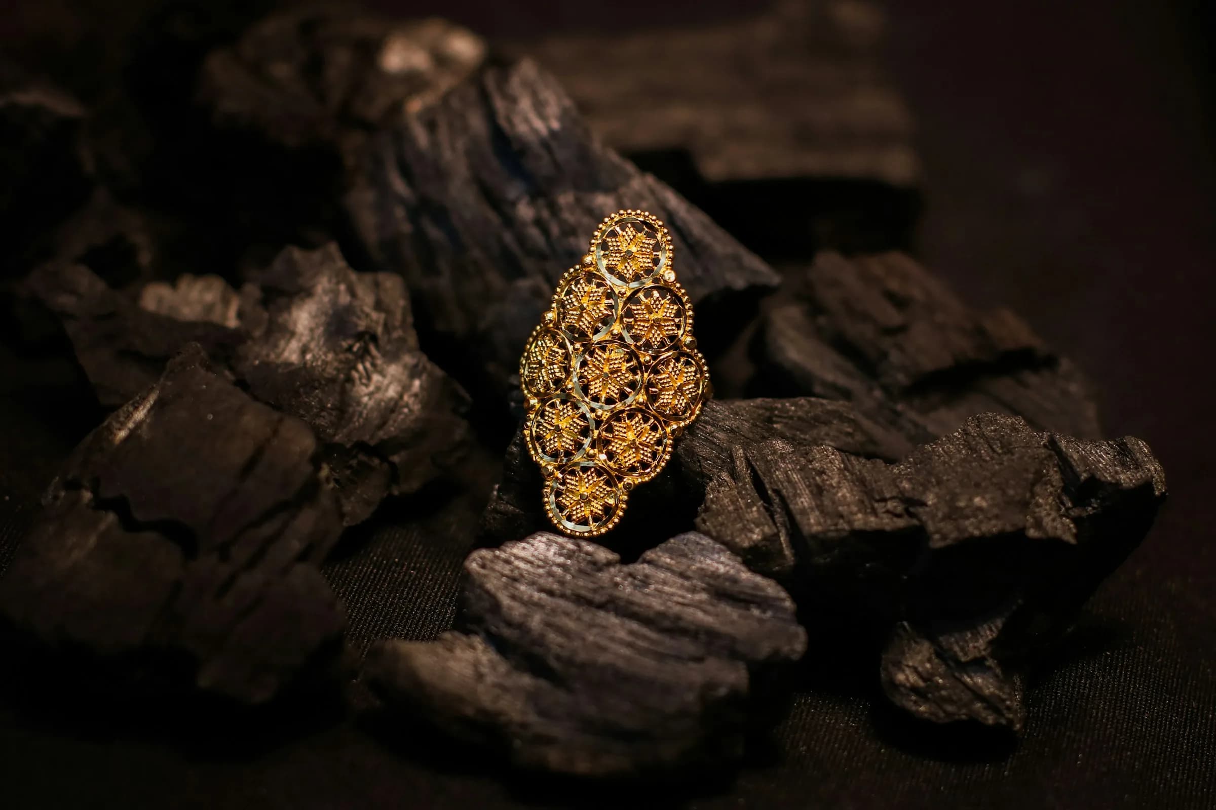 Filigraner Goldring auf dunkler Holzkohle